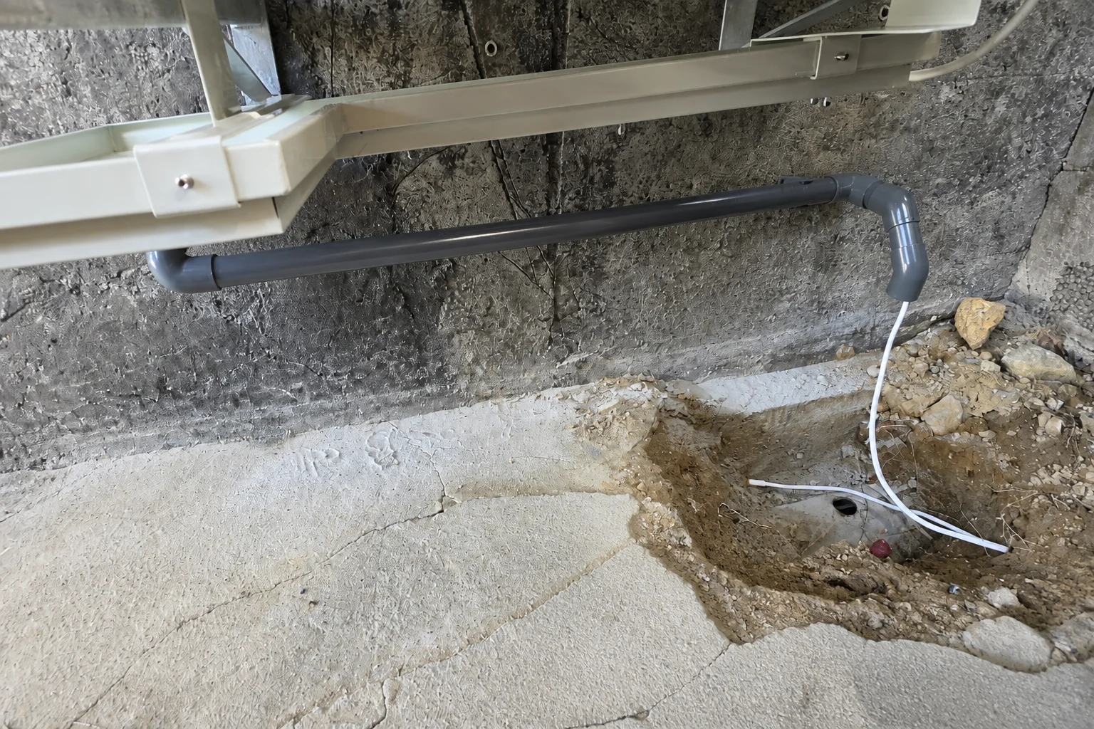 Detalj av rørføring fra varmepumpens utedel mot felles drenering under arbeid